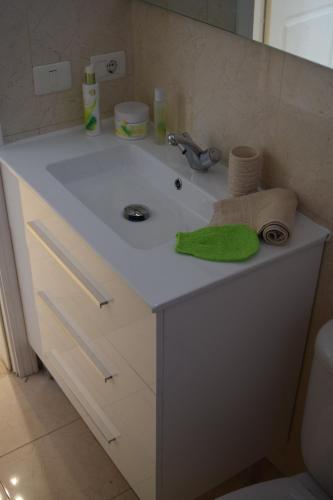 a bathroom sink with a green towel and a sponge at Andromeda in Palm-Mar