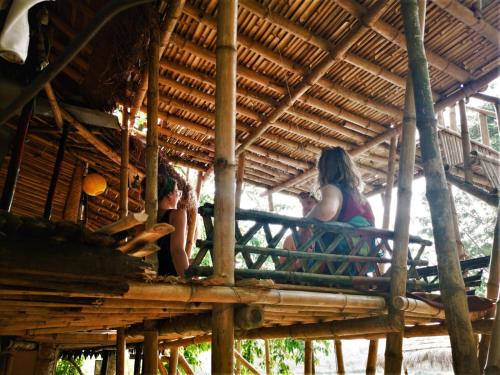 a woman sitting on a porch of a hut at Happy Lemon Tree lodge in Sauraha