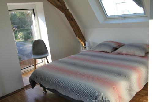 um quarto com uma cama com uma janela e uma cadeira em Gite du Moulin de Balzac em Artannes-sur-Indre