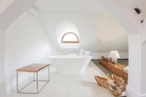 a white bathroom with a white tub and a table at Hotel Jakubus in Wilków