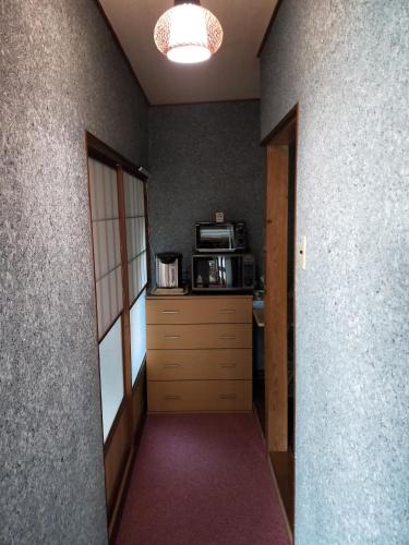 a hallway leading to a kitchen with a microwave at Izu Hokkawa Seaside Guesthouse 伊豆北川の家 in Higashiizu