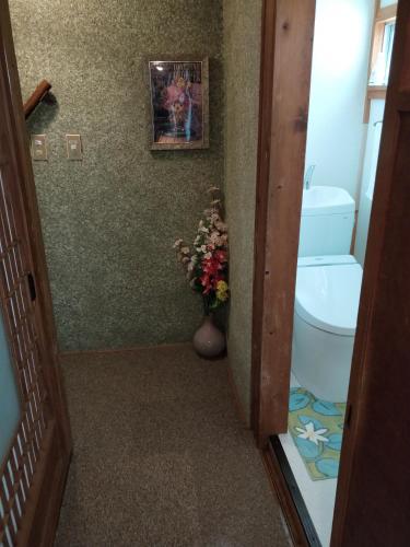 a bathroom with a toilet and a vase of flowers at Izu Hokkawa Seaside Guesthouse 伊豆北川の家 in Higashiizu