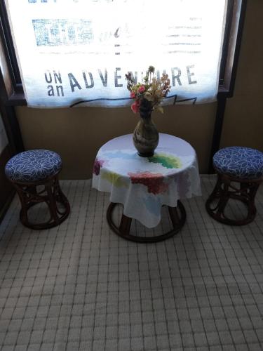 a table with a vase on it with two chairs at Izu Hokkawa Seaside Guesthouse 伊豆北川の家 in Higashiizu