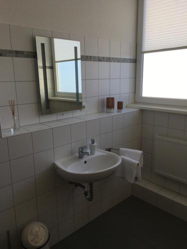 a white bathroom with a sink and a mirror at Ferienwohnung Schleswig in Schleswig