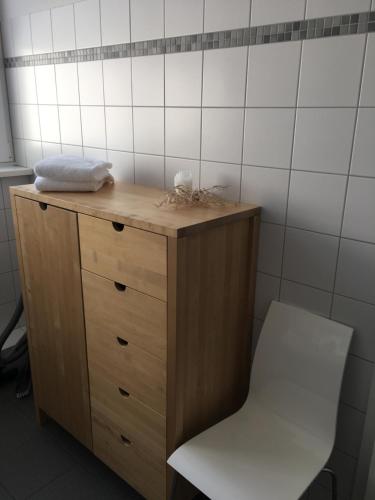 een houten dressoir met een witte stoel in de badkamer bij Ferienwohnung Schleswig in Schleswig