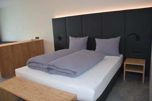 a bedroom with a large white bed with a black headboard at Garden-Suite Faselehof in Marlengo