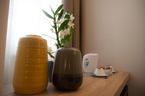 two vases sitting on top of a wooden table with flowers at Hotel Dimorae Rooms and Suites - Apartments in Civitanova Marche