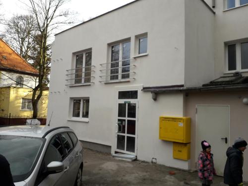 a woman standing in front of a white house at Sol De Sopot in Sopot