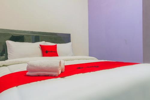 a bed with a red and white blanket on it at RedDoorz Plus @ Tuparev Cirebon 2 in Cirebon