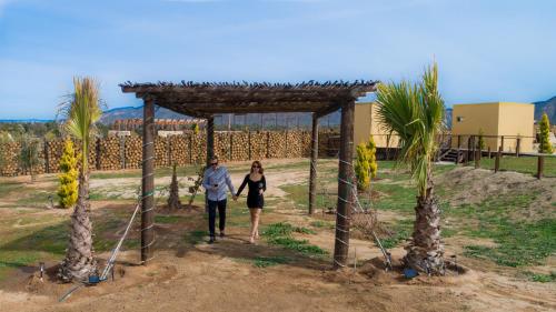 a man and a woman walking under a wooden structure at Cuatro Lunas Hotel Boutique in Valle de Guadalupe