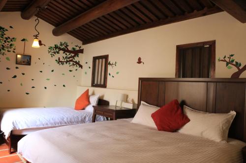 a bedroom with two beds and a wall with trees on it at Longmen Inn Bed and Breakfast in Jinning