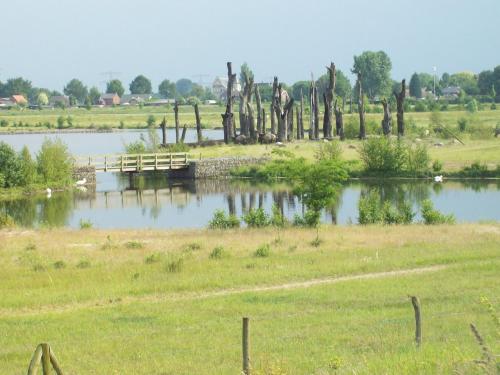 a bridge over a lake with trees and a field at Vakantie Appartementen Engelen in Stevensweert
