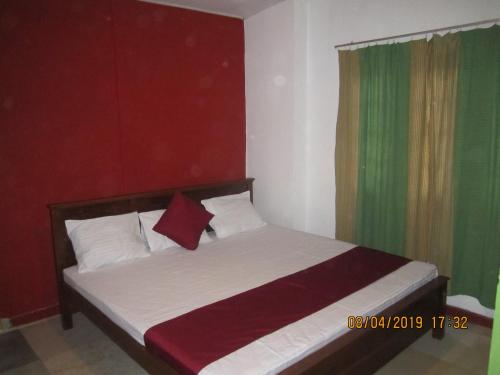 a bedroom with a bed with red and green curtains at Tree House Holiday Home in Bandarawela