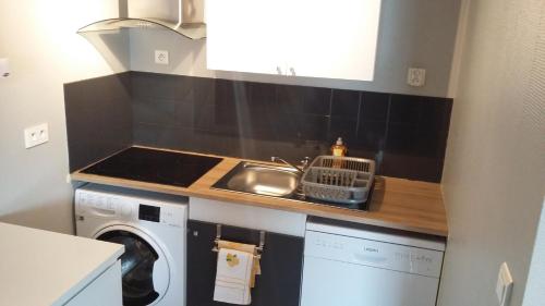 een keuken met een wastafel en een wasmachine bij L'Océane ( Résidence La Joséphine ) in Les Sables-dʼOlonne