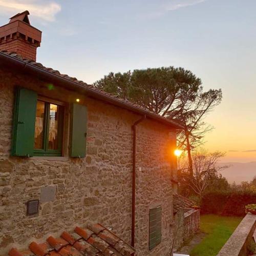 レッジェッロにあるPodere I Rovai-apt IL RIFUGIO- in the heart of Tuscanyの日没を望む窓付きのレンガ造りの建物