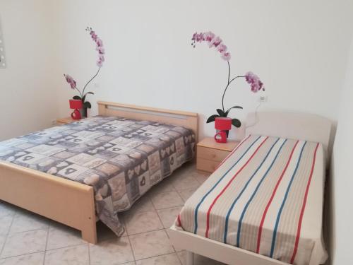 1 dormitorio con 1 cama y 2 jarrones con flores en AGLI OLEANDRI, en Gorizia