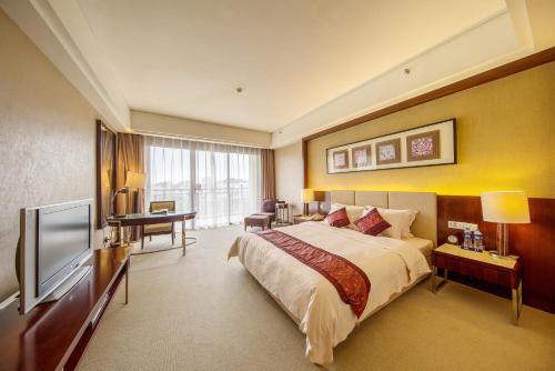 a hotel room with a bed and a flat screen tv at Dongguan Richwood Garden Hotel in Dongguan