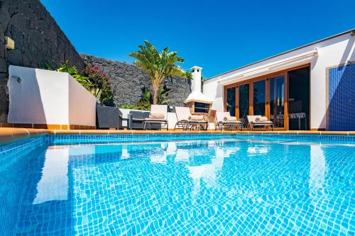 a swimming pool with chairs and a house at Villa Feel in Tías