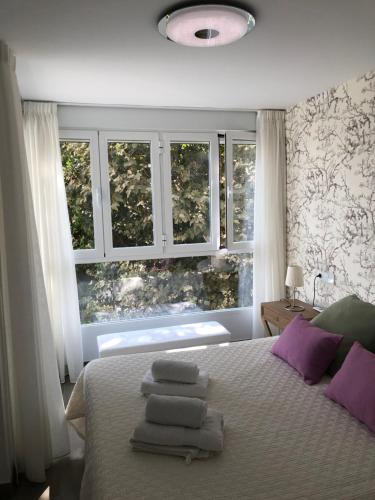 1 dormitorio con 1 cama con almohadas y ventanas moradas en Vistamar Beach Luxury - 1ª Línea De Playa En Torre del Mar, Piscina y Apartamiento, en Torre del Mar