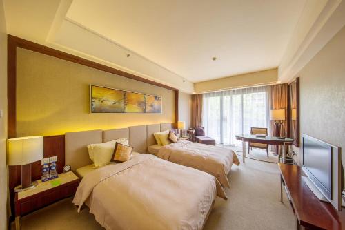 a hotel room with two beds and a flat screen tv at Dongguan Richwood Garden Hotel in Dongguan