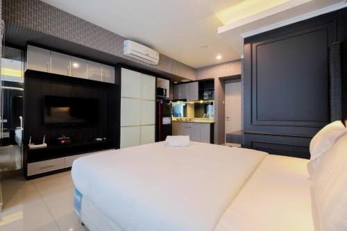a bedroom with a large white bed and a fireplace at Fabulous Studio Grand Kamala Lagoon Apartment By Travelio in Pulosirih