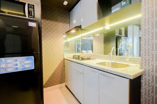 a small kitchen with a sink and a microwave at Fabulous Studio Grand Kamala Lagoon Apartment By Travelio in Pulosirih
