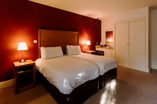a hotel room with two beds and a lamp at Chevin Country Park Hotel & Spa in Otley
