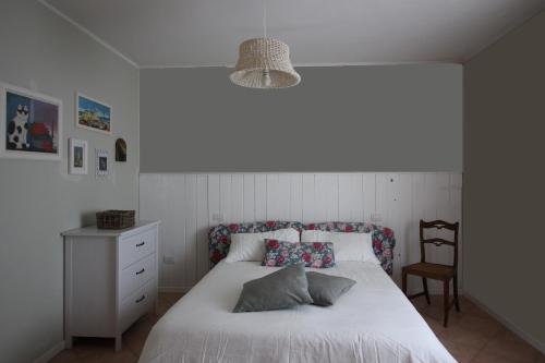 um quarto com uma cama branca e uma cadeira em Casa S.Paolo em Rimini