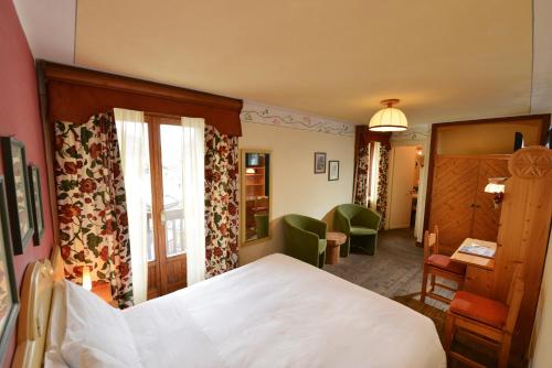 a bedroom with a bed and a desk and a chair at Hotel Du Grand Paradis - 1899 Auberge Boutique in Cogne