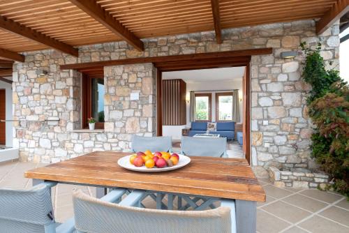 a plate of fruit on a wooden table on a patio at Villa Almira Luxury Apartments in Ouranoupoli