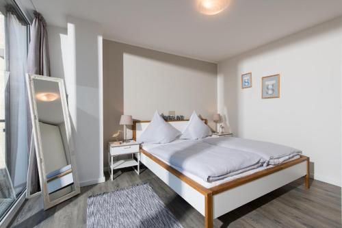 biała sypialnia z łóżkiem i lustrem w obiekcie Kompass w mieście Olpenitz