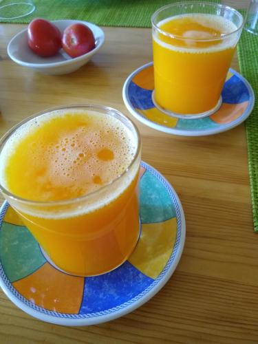 two cups of orange juice on plates on a table at Hostal D'Éller in Éller