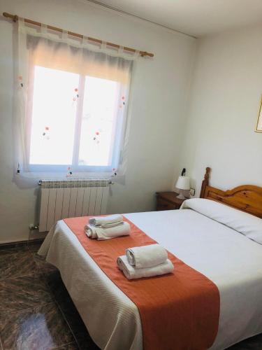 a bedroom with two towels on a bed with a window at Hostal Restaurante Taibilla in Nerpio