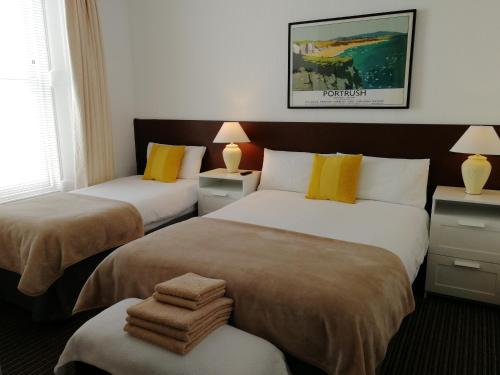two beds in a hotel room with towels on them at Malvern House in Portrush