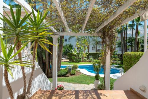 a patio with palm trees and a swimming pool at Apartamento Marbella Real 2D in Marbella