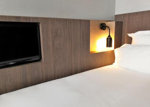 a bedroom with a bed and a flat screen tv at Libertel Gare Du Nord Suede in Paris