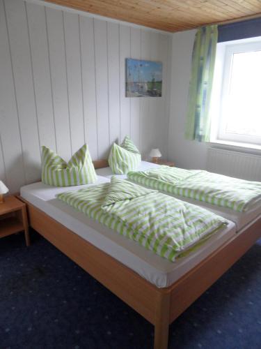 a bedroom with two beds with green sheets and a window at Haus Jane in Dornum