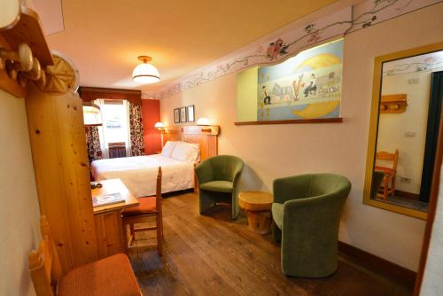 a hotel room with a bed and two green chairs at Hotel Du Grand Paradis - 1899 Auberge Boutique in Cogne
