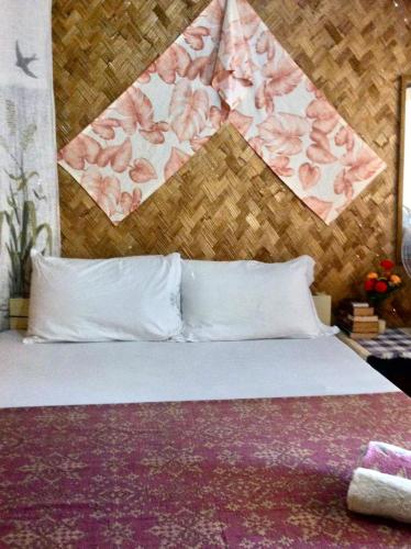 a bed with white pillows and a floral head board at Camp Talusi Hilltop Overlooking in El Nido