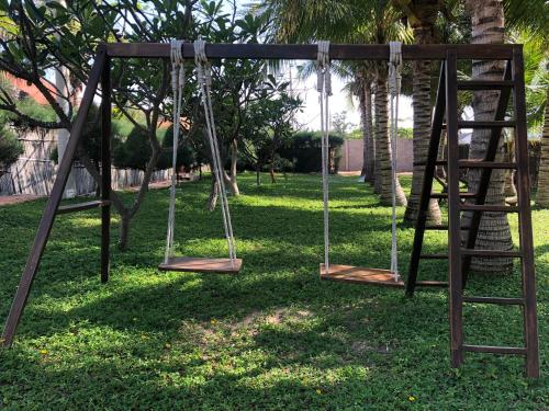 two swings in a park with trees at Full Moon Village Resort in Mui Ne