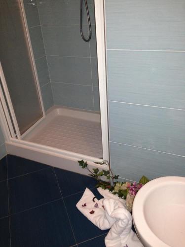 a bathroom with a shower and a sink and towels at Hotel Adler in Foppolo