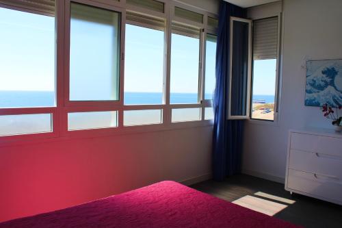 a bedroom with windows and a pink bed with a pink rug at Beach Apartment Guadalmar in Málaga