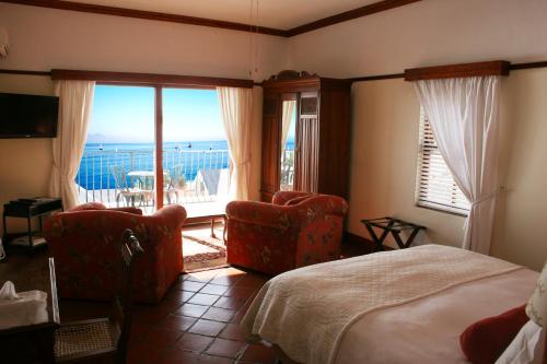 a hotel room with two beds and a balcony at Berg en Zee Guesthouse in Gordonʼs Bay