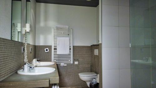 a bathroom with a toilet, sink and mirror at Hotel Bliss in Bruges