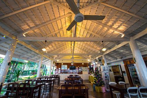 un restaurante con ventilador de techo, mesas y sillas en Rocky Point Resort, en Thap Sakae