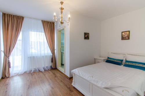 a white bedroom with a bed and a chandelier at Vila Maria in Râşnov