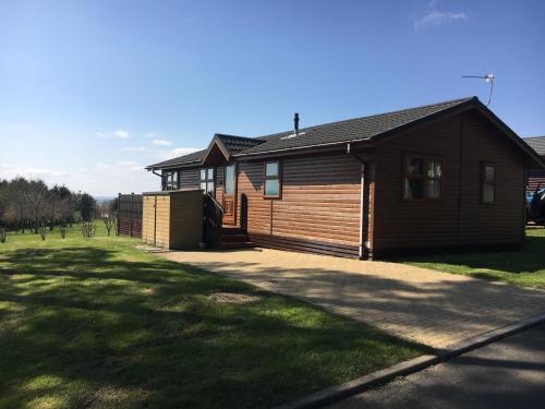 a wooden cabin with a driveway in front of a yard at Millie,s View 18 hole free Golf in Swarland