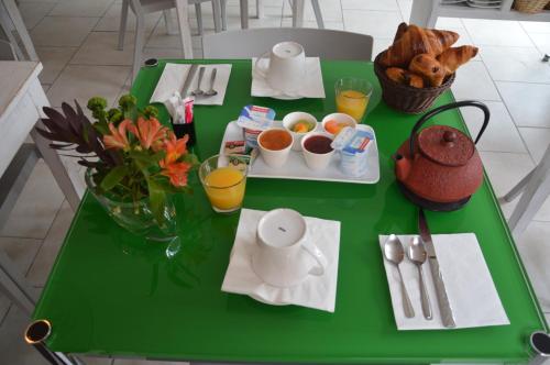 una mesa verde con desayuno y bebidas. en Hotel le Castellamar en Sainte-Maxime