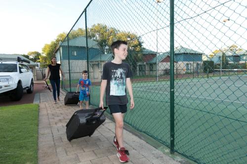 a young boy with a suitcase on a tennis court at Amalfi Resort in Busselton