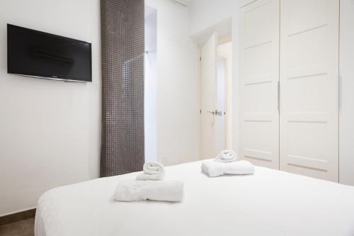 a white bedroom with two towels on a bed at Stay U-nique Apartments Eixample Center in Barcelona